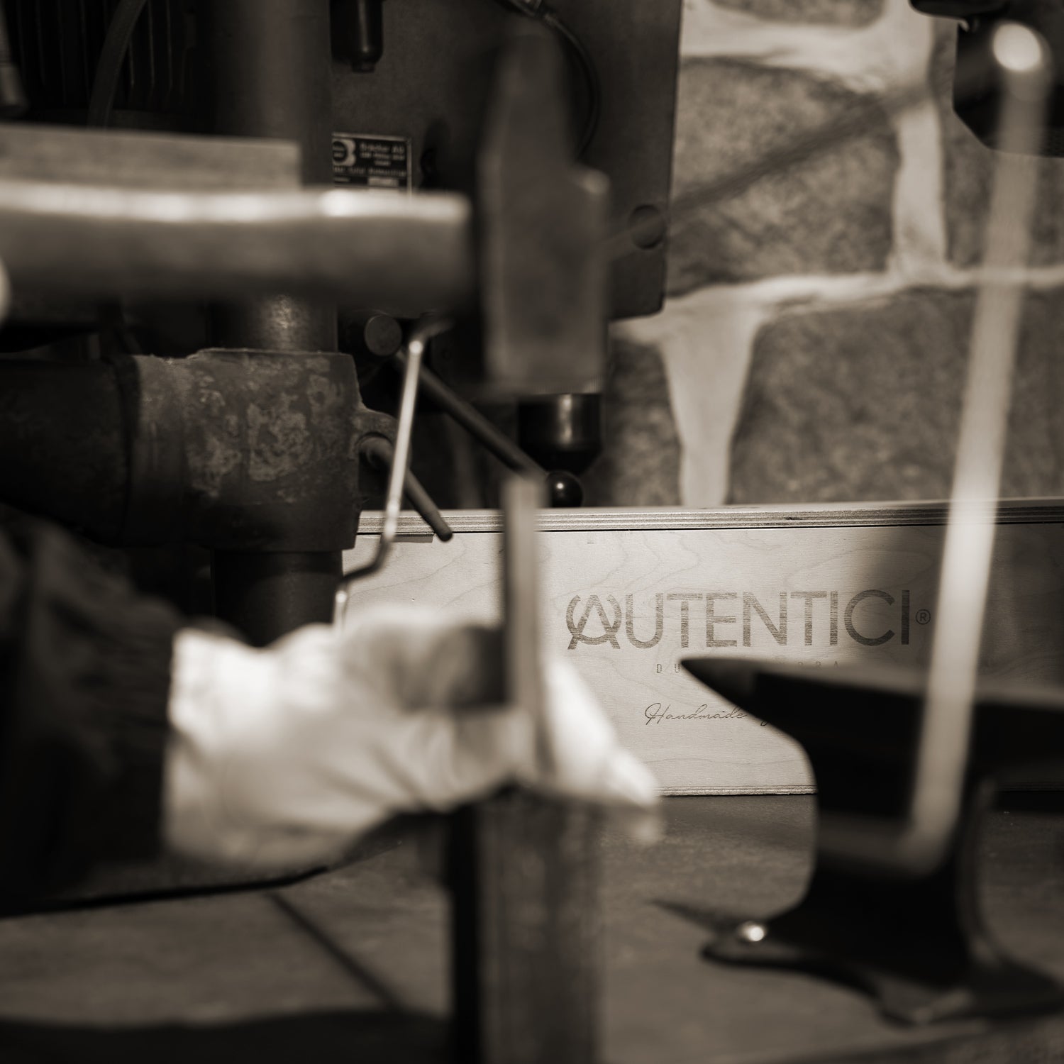 Artisan at work in a workshop with tools in the foreground and wooden packaging featuring a premium car accessory logo in the background, showcasing craftsmanship and attention to detail. Autentici sun shade for car windshield. Protetor solar para para-brisas de automóvel clássico.