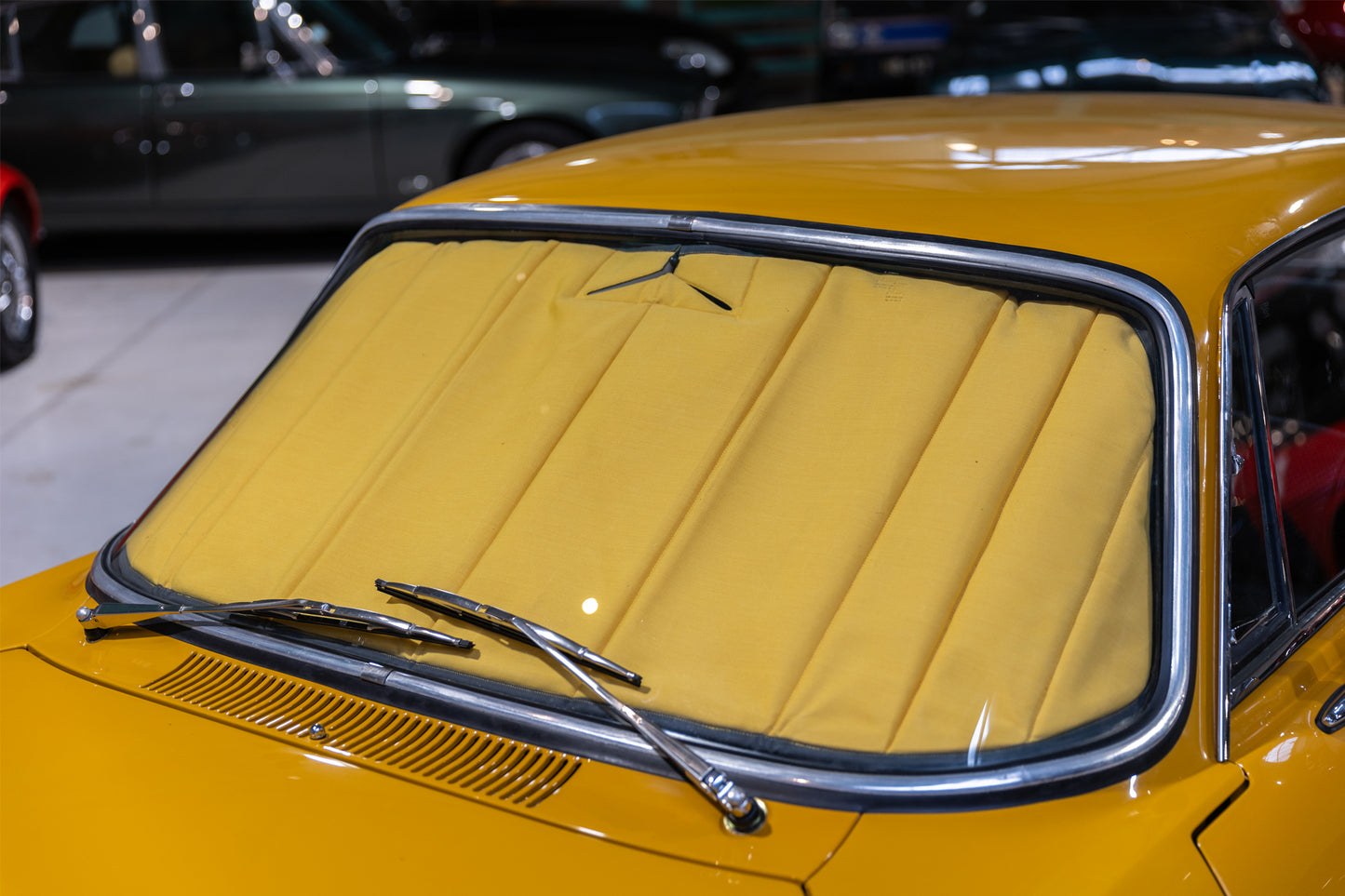 Close-up of a classic yellow car fitted with a premium yellow sunshade, highlighting tailored interior protection and vintage style. Autentici sun shade for car windshield. Protetor solar para para-brisas de automóvel clássico.