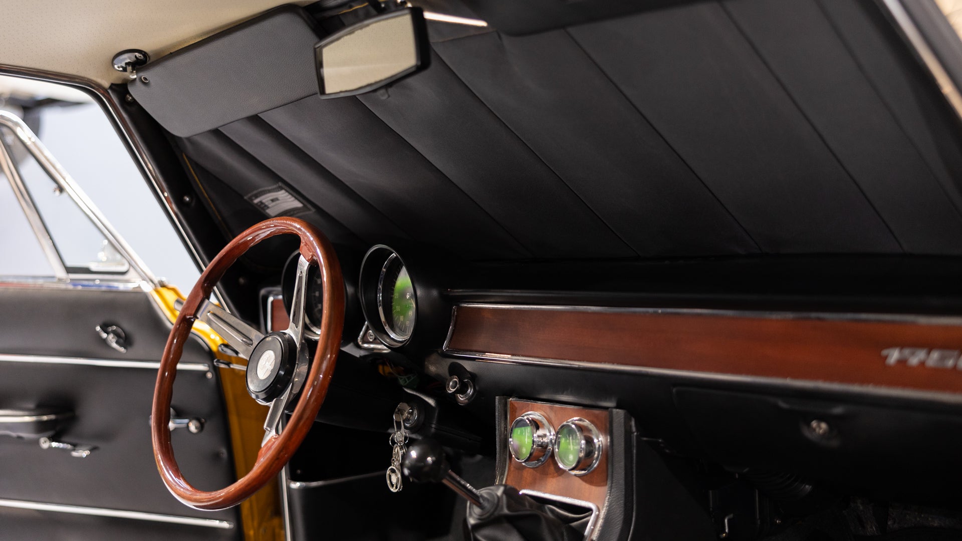 Interior of a classic car featuring a wooden steering wheel, a custom black sunshade, and vintage dashboard details, emphasizing timeless elegance and tailored car interior protection. Autentici sun shade for car windshield. Protetor solar para para-brisas de automóvel clássico.