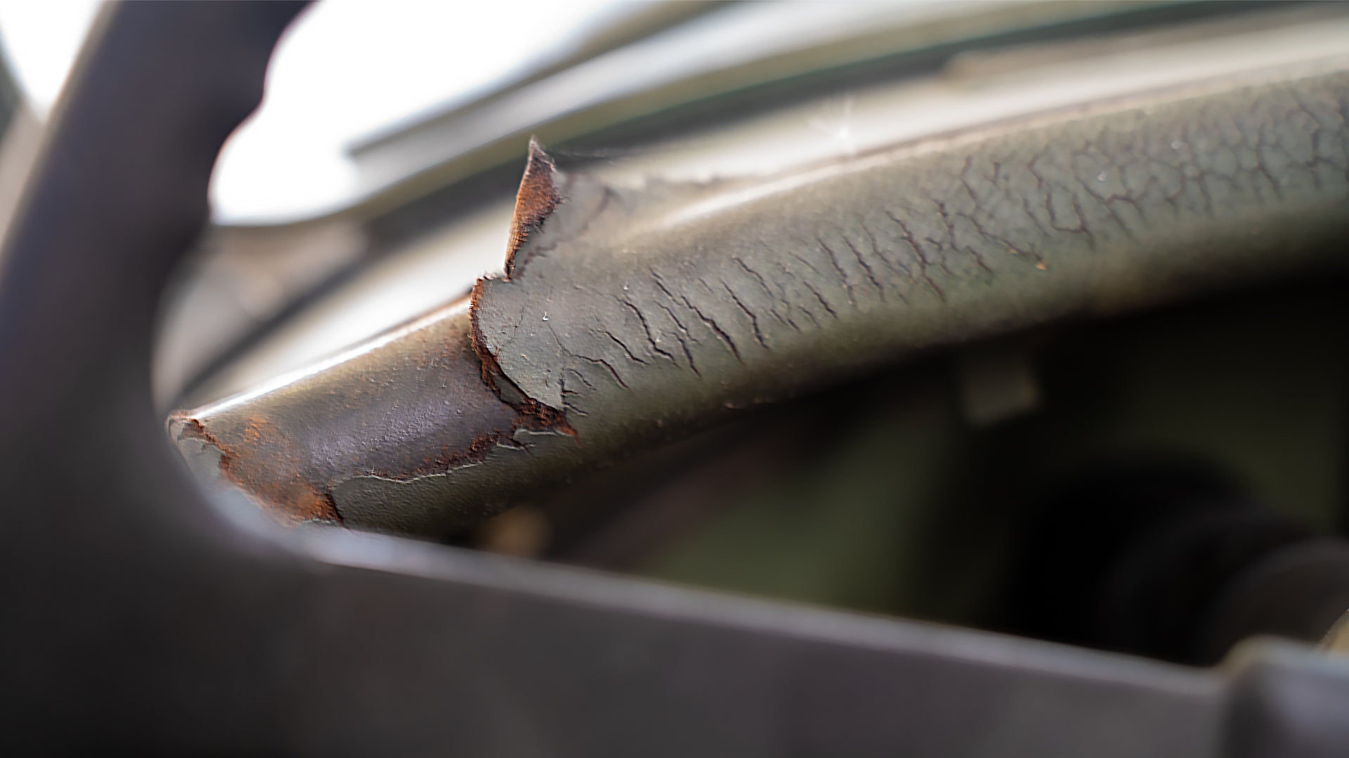 Close-up of a sun deteriorated steering wheel in a classic car, highlighting aged materials and the need for interior restoration.