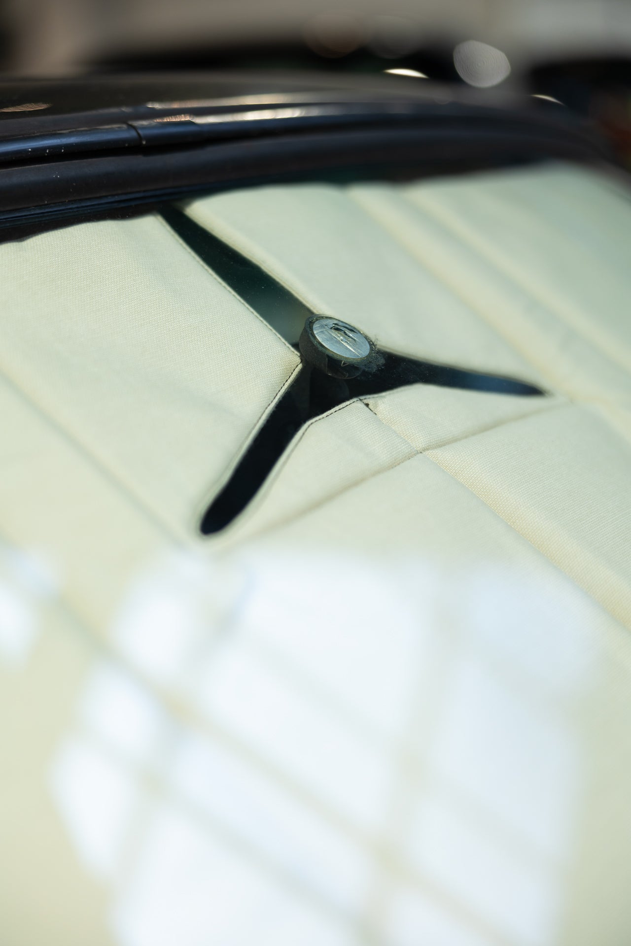 Detailed close-up of a Y-shaped opening in a premium sunshade designed for a classic car, showcasing precision fitting for the rearview mirror. Autentici sun shade for car windshield. Protetor solar para para-brisas de automóvel clássico.