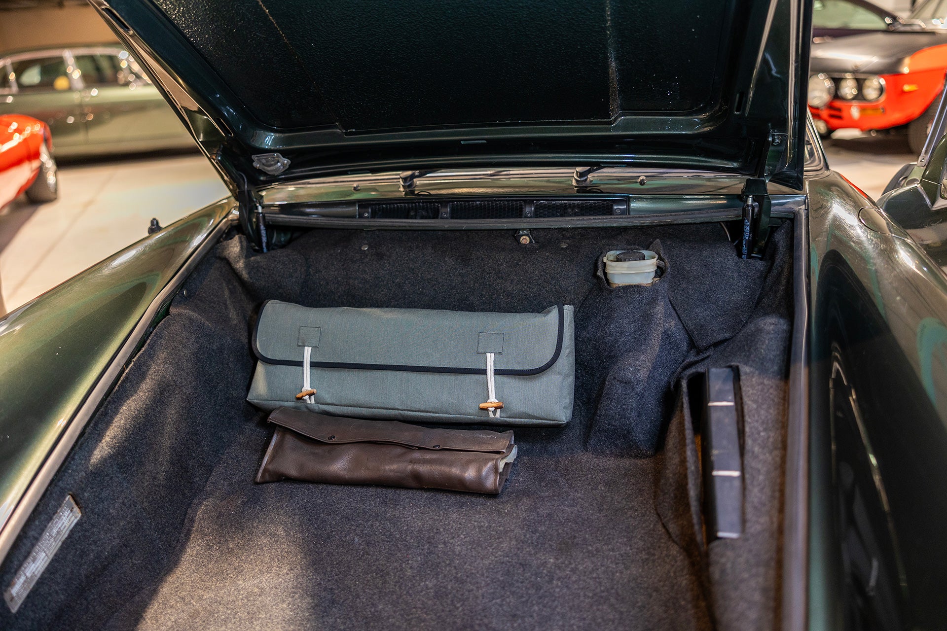 Classic car trunk with an Autentici sunshade stored in its premium bag, alongside a vintage leather tool kit, highlighting elegant organization and practicality. 