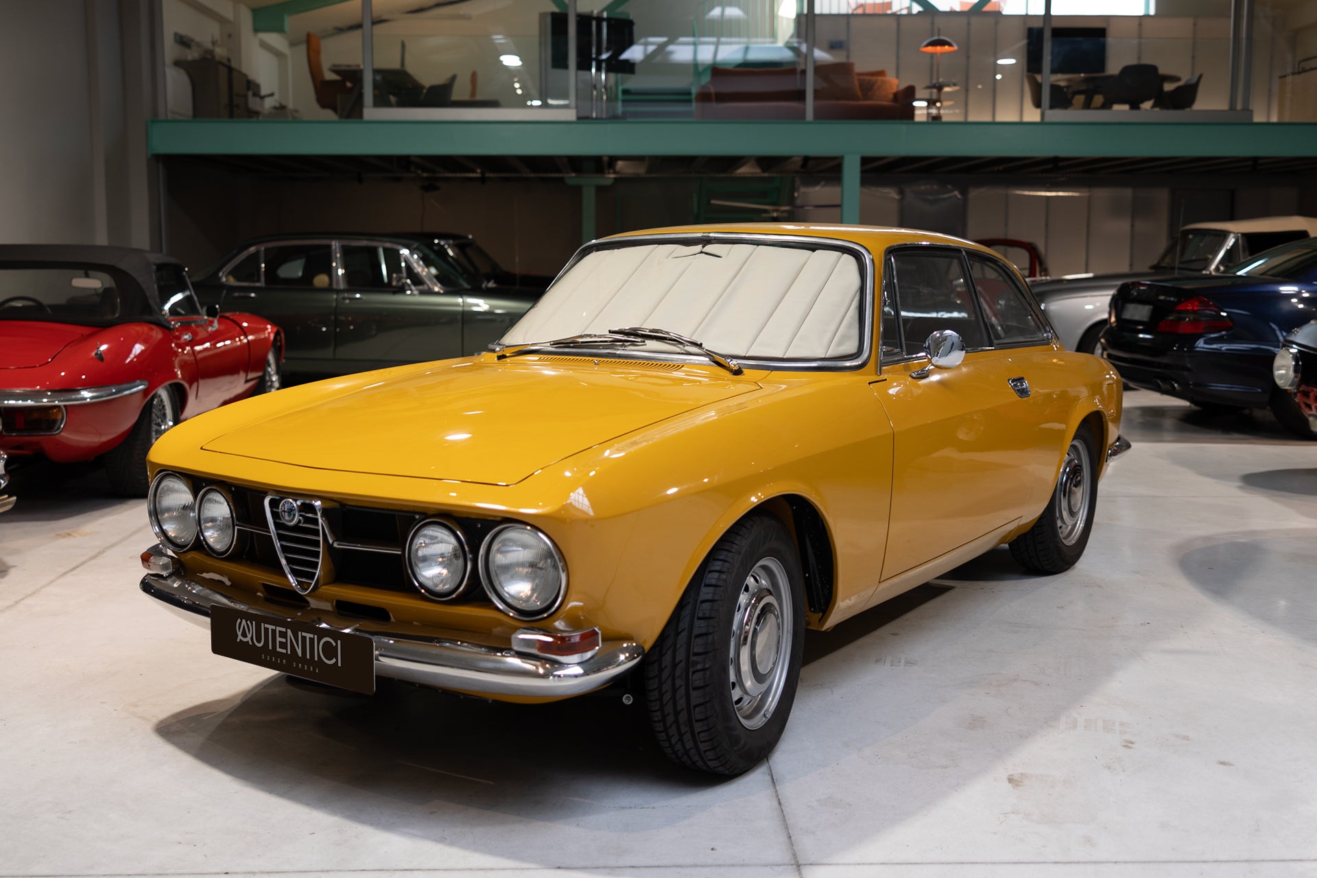 Classic yellow car fitted with a premium beige sunshade in an indoor showroom, showcasing luxury interior protection and timeless design. Autentici sun shade for car windshield. Protetor solar para para-brisas de automóvel clássico.