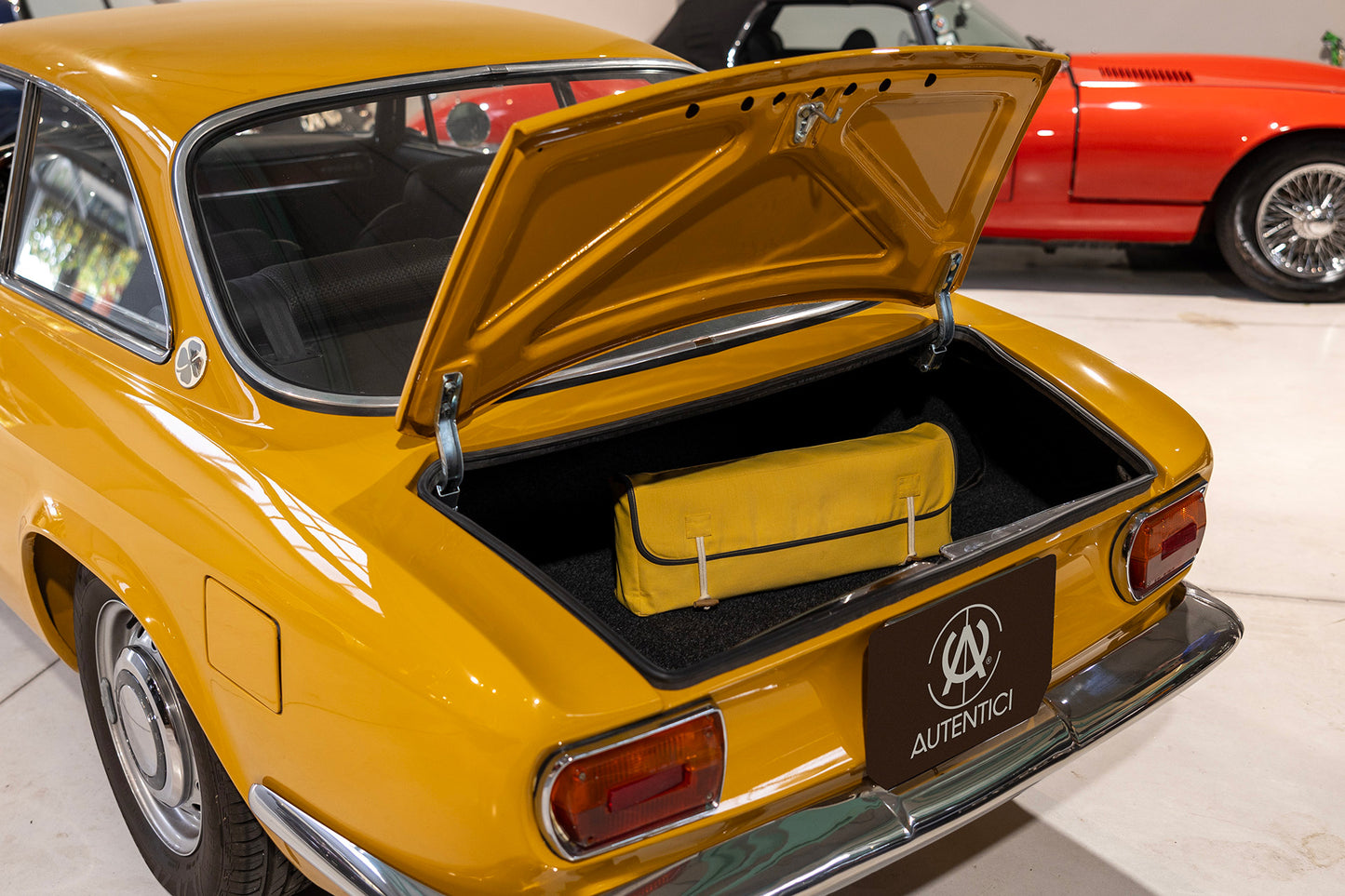 Open trunk of a classic yellow car with a premium yellow storage bag neatly placed inside, showcasing practicality and tailored accessory protection.  Autentici sun shade for car windshield. Protetor solar para para-brisas de automóvel clássico.