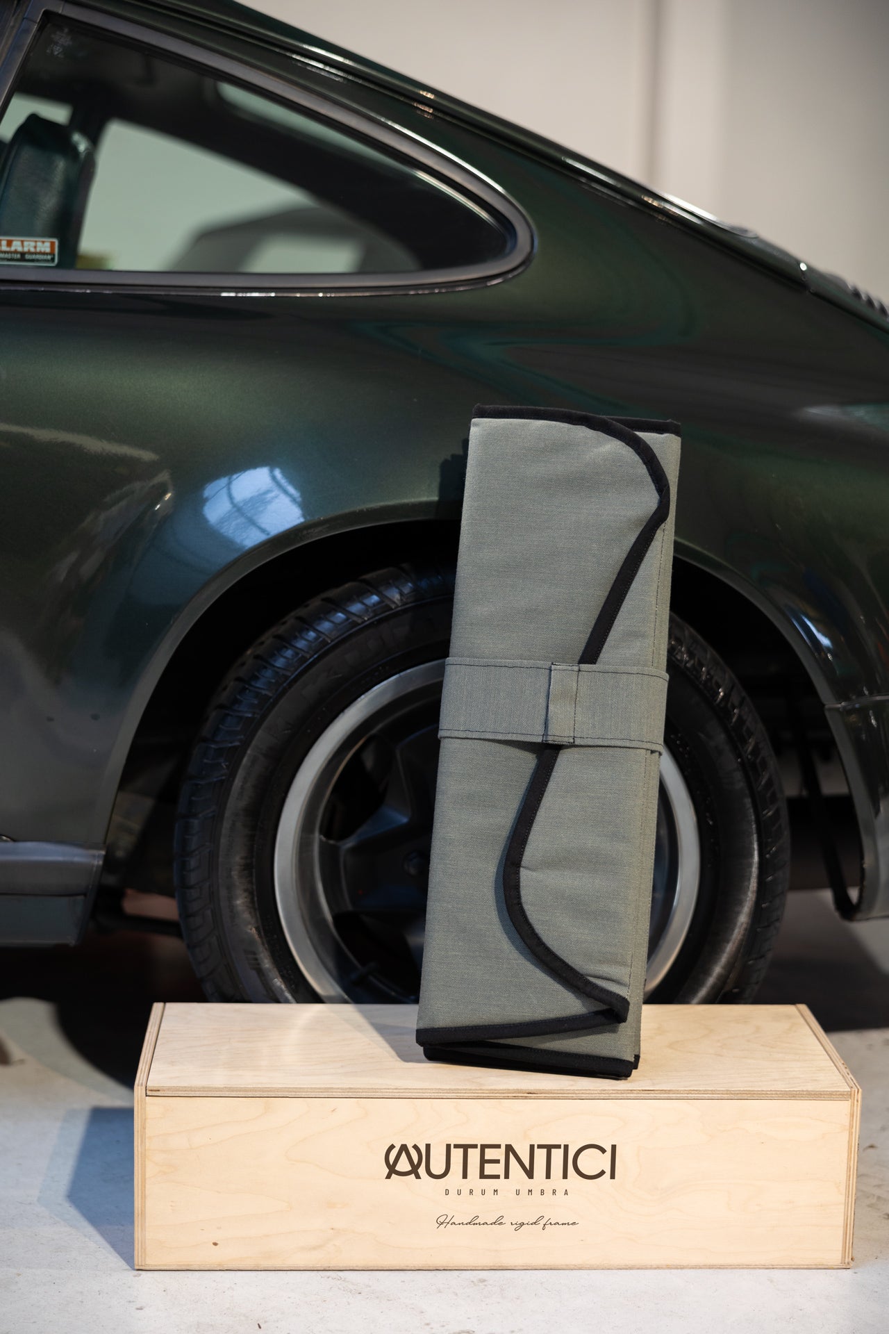 Folded premium sunshade for classic cars, displayed on a branded Autentici wooden box, emphasizing quality craftsmanship and elegant storage solution. Autentici sun shade for car windshield.