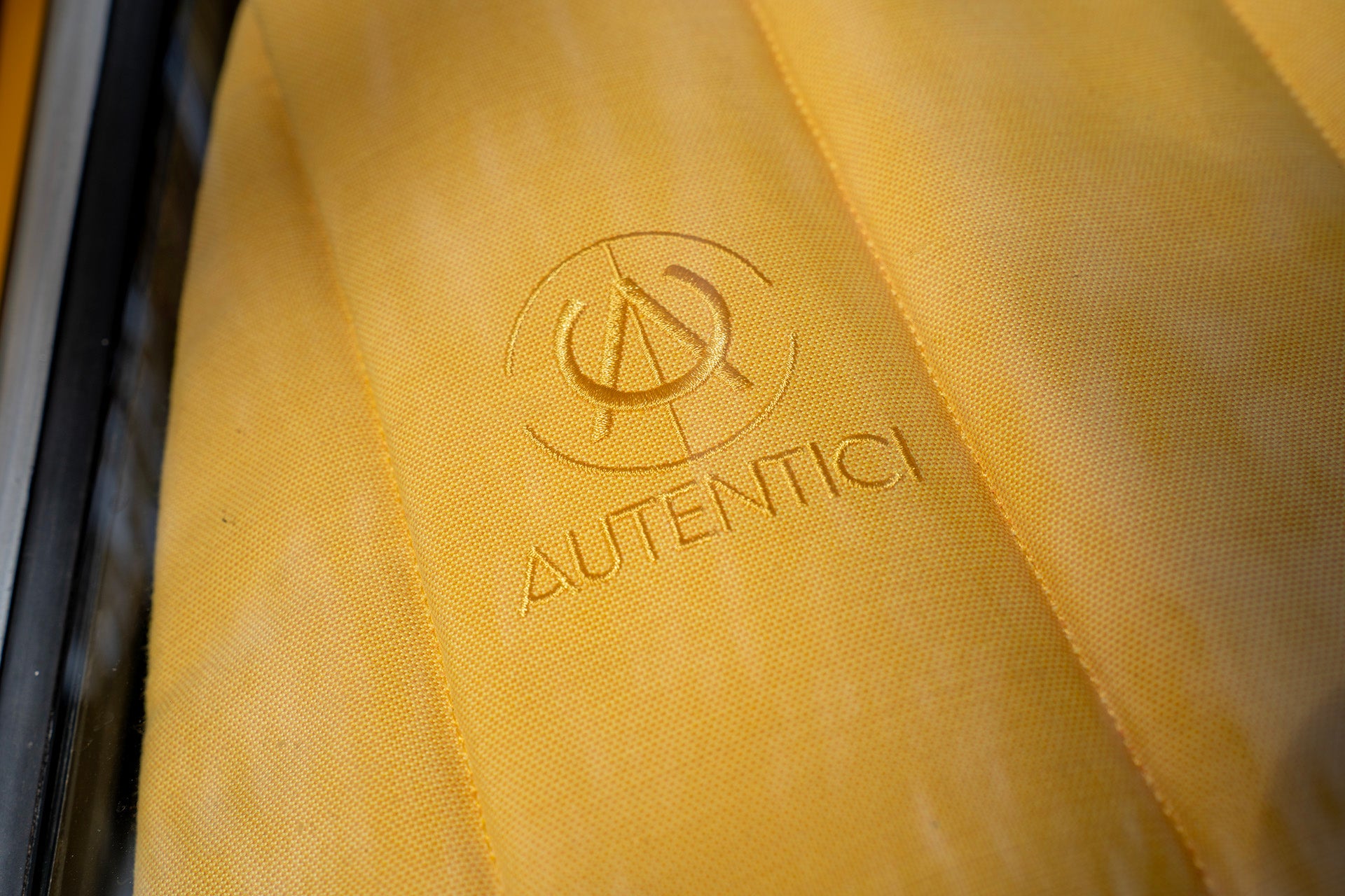 Close-up of a premium car sunshade with an embroidered logo, showcasing luxurious craftsmanship and attention to detail for classic cars. Autentici sun shade for car windshield. Protetor solar para para-brisas de automóvel clássico.