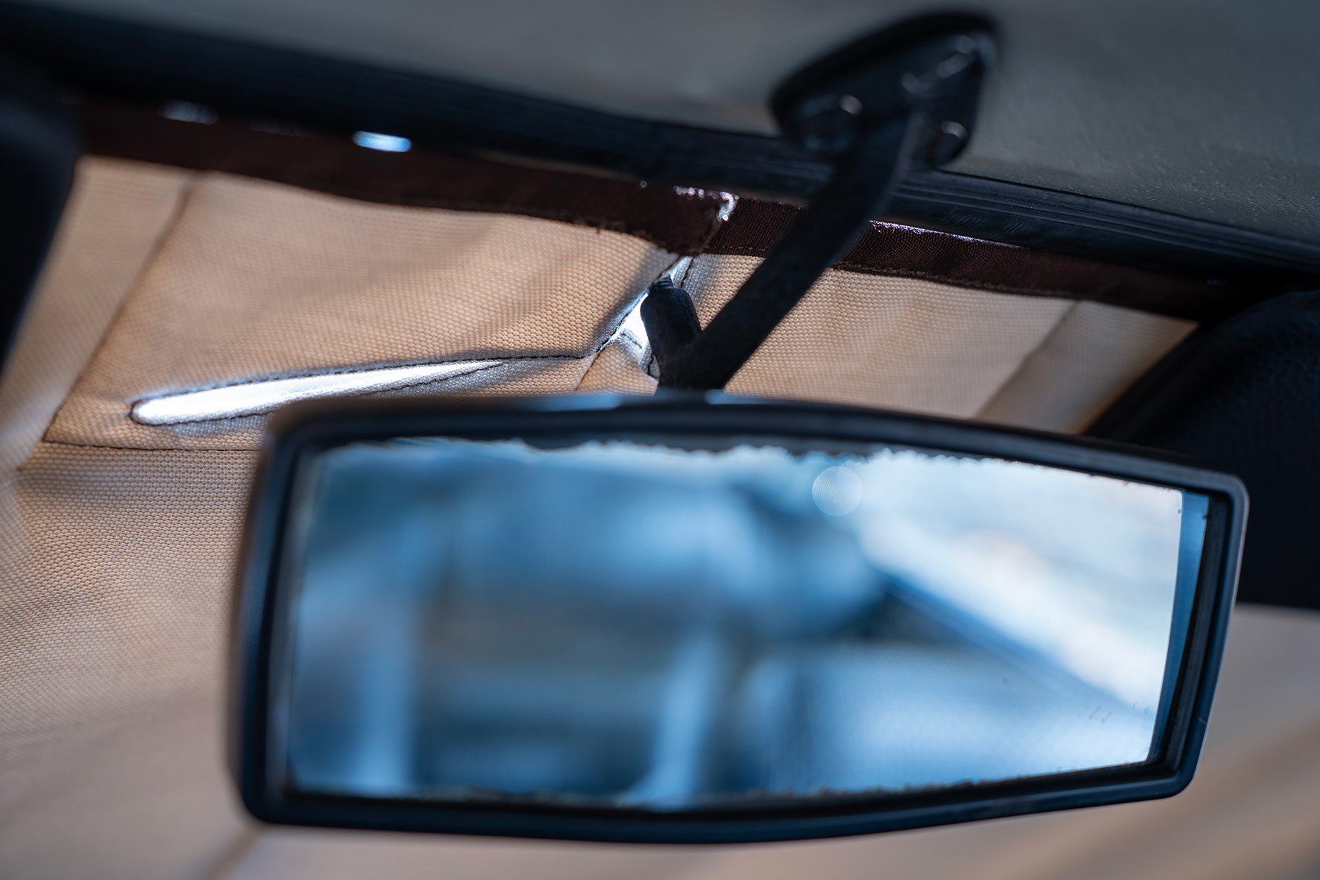  Detail of a rearview mirror passing through a custom opening in a premium car sunshade, showcasing precise design and tailored functionality for classic cars.  Autentici sun shade for car windshield. Protetor solar para para-brisas de automóvel clássico.